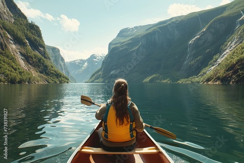 Back view of a young woman paddling a canoe on a serene lake surrounded by majestic fjords Capturing a moment of adventure and tranquility