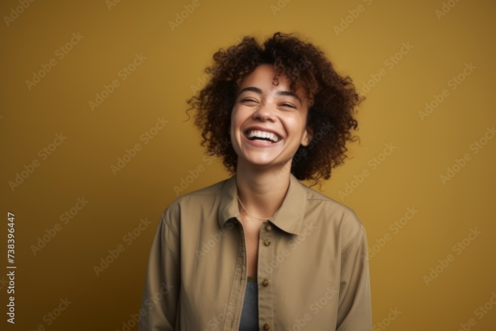 Portrait of a happy young african american woman laughing over yellow background Portrait of a happy young african american woman laughing over yellow background