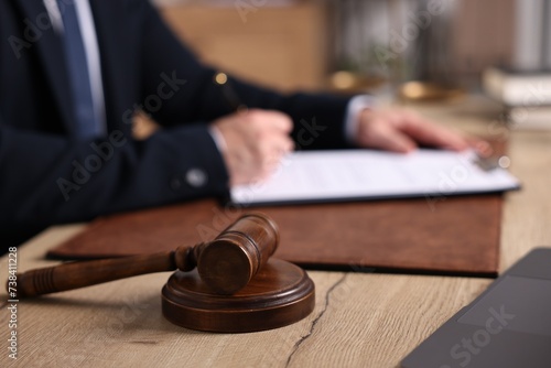 Notary writing notes at wooden table in office. focus on gavel
