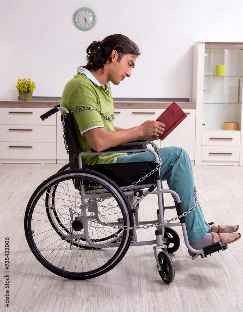 Young male invalid in wheel-chair suffering at home Young male invalid in wheel-chair suffering at home
