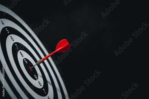 Bullseye is a target of business. Dart is an opportunity and Dartboard is the target and goal. challenge in business marketing business success concept. Dark black background. Cpoy space for text. photo