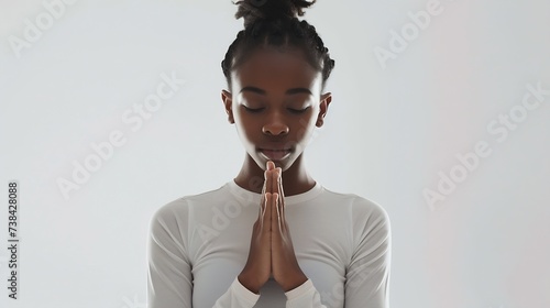 Meditation concept Beautiful young black woman stands in meditative pose enjoys peaceful atmosphere holds hands in praying gesture isolated over white background has sense of inner pea : Generative AI photo
