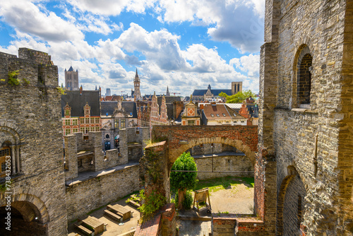 The skyline and historic old town and St. Veerleplein market square with the church towers and belfry rising above medieval Gravensteen Castle in Ghent, Belgium.
