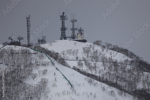 	望遠レンズで撮影した雪山とその上に立つ人工物のアップ
