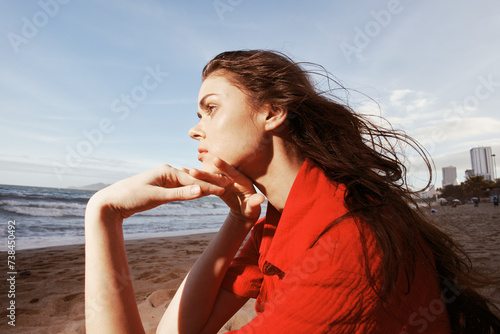 Relaxed Beauty: A Happy, Carefree Woman Sitting on a Sandy Beach, enjoying the Beauty of a Sunset over the Ocean