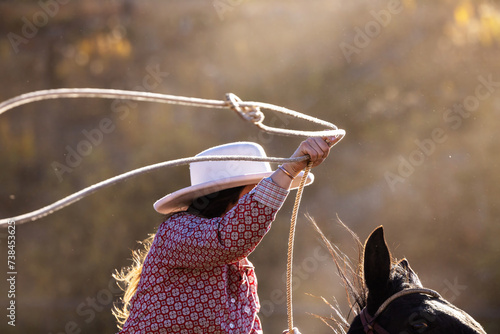 Foto Colorado Cowgirl swinging a lasso rope horseback