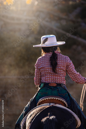 Fotografija Colorado cowgirl riding horse in dusty pen with rope