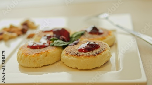 For breakfast, homemade fried syrniki on table, topped with jam. Dessert option features syrniki with sweet jam. Enjoy this delightful dessert with jam for a satisfying start to your day.