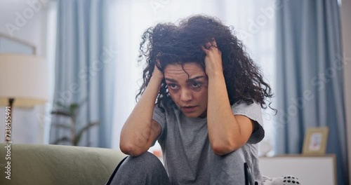 Woman, frustrated and depression on sofa in home with schizophrenia, mental health and burnout. Psychology, person and headache with anxiety, trauma and suffering on couch in living room with stress photo