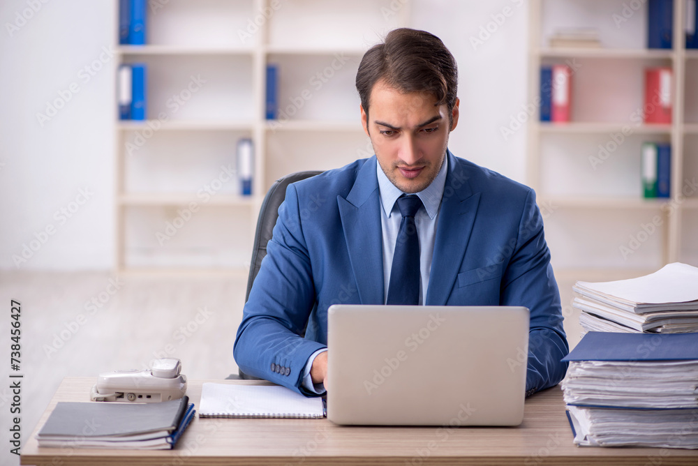 Young male employee and too much work in the office Young male employee and too much work in the office
