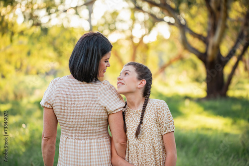 Pre-teen girl leaning on mother's shoulder in natural bush setting photo