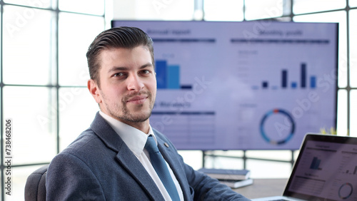 A businessman man in a close-up in a jacket with graphs on the background looks at the camera