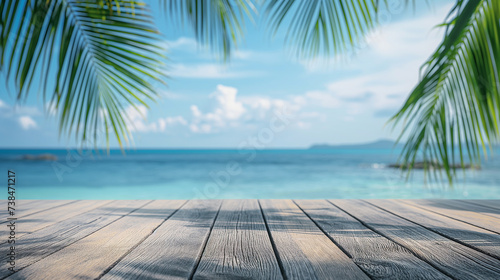 Top of wooden table with sea view and palm leaves Blur of calm sea and sky at tropical beach background for product display montage.
