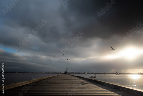 Como jetty with looming clouds at Perth, Western Australia. Moody, cloudy beautiful landscape scenery with flying seagull at the swan river