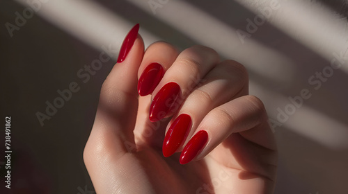 A woman's hand with short almond nails painted in red, Soft light, creating a feminine and sophisticated atmosphere.