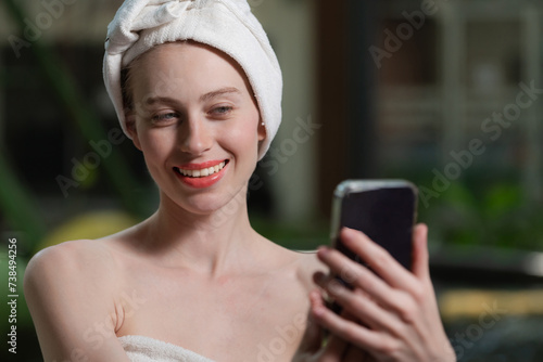 Portrait of close up beautiful caucasian woman in white towel taking video of calm and relaxing nature by using her mobile phone. Pretty girl with beautiful skin take photo. A Side view. Tranquility.