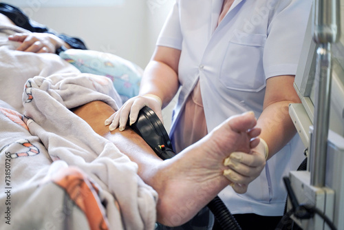 physical therapist using electrical muscle stimulation (EMS) at elderly patient's legs in nursing homes