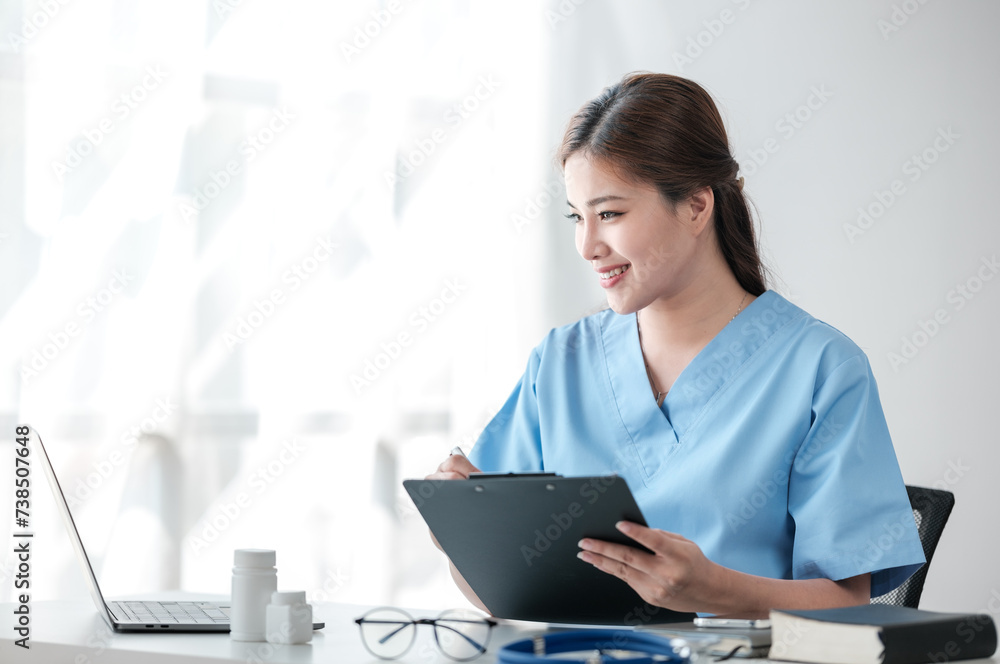 Asian female doctor working on laptop, filling out paperwork, patient medical history, reviewing documents at her workplace medical and health concept Asian female doctor working on laptop, filling out paperwork, patient medical history, reviewing documents at her workplace medical and health concept