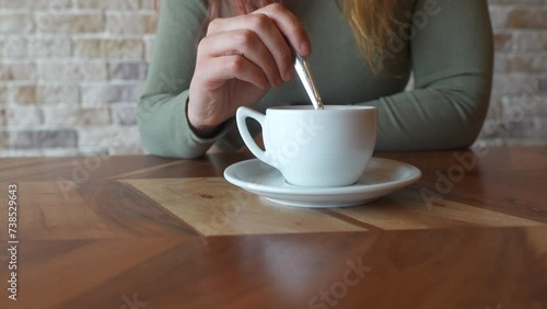 Close-up of a woman's hands stirring a white coffee cup photo