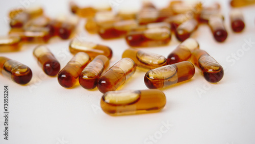 Brown liquid gel medicine fish oil omega capsule close up on white background