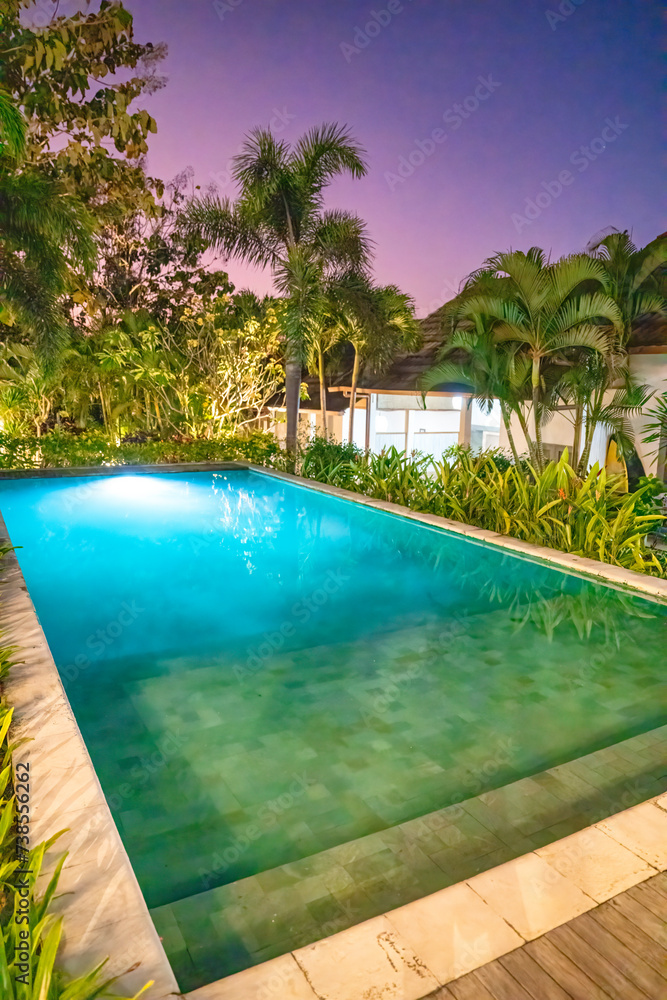A beautiful tropical resort with pool at night with palms
