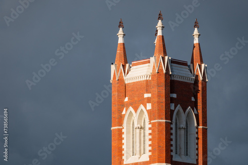 Close up view of a tall historic church steeple against a dark sky photo