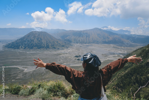 An Asian girl standing on a hill track in Bromo, enjoying view of Bromo, a wonderful scenery in dramatic hill photo