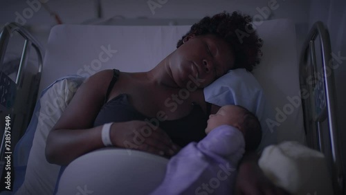 Black Woman with Curly Hair Resting in Delivery Room With Infant Child photo