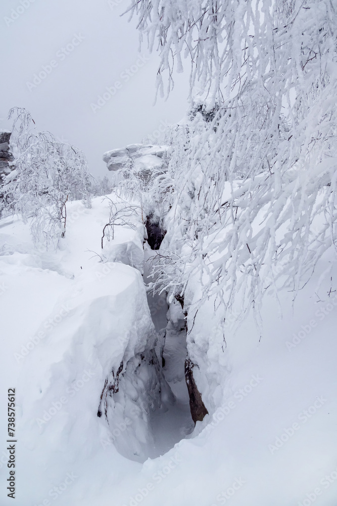 Narrow path through snow drifts between rocks