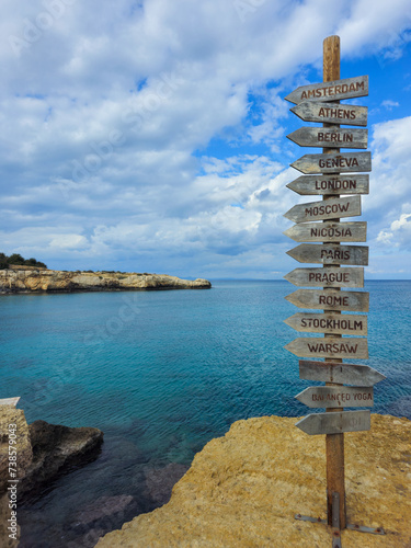 Signpost of direction of European capital cities on a wooden board in the coast against cloudy sky