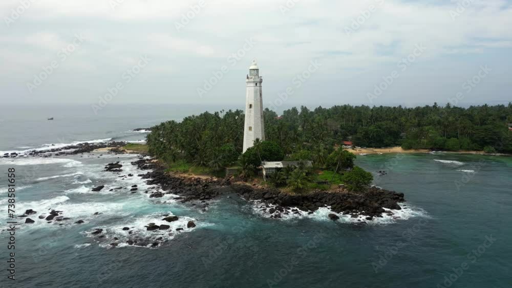 White colonial Dondra Head lighthouse surrounded by the ocean and palms on the jungle coast of Sri Lanka White colonial Dondra Head lighthouse surrounded by the ocean and palms on the jungle coast of Sri Lanka