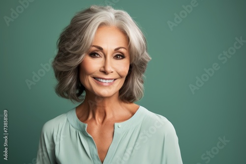 Portrait of a happy senior woman with grey hair, over green background.