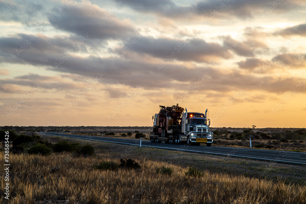 Semi trailer truck driving at dusk on Eyre Highway along the Nullarbor Plain Semi trailer truck driving at dusk on Eyre Highway along the Nullarbor Plain