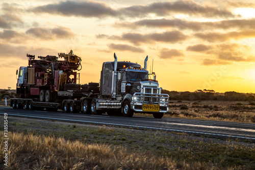 Semi trailer truck driving at dusk on Eyre Highway along the Nullarbor Plain photo