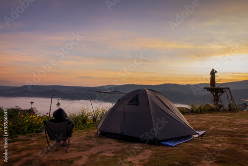 Tourist tent on camping site on the meadow next to the foggy during sunset, Thailand. Beautiful sunset twilight sky