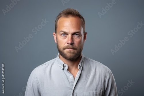 Portrait of a young man looking at camera over grey background. © Loli
