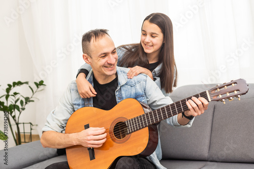 smiling father showing daughter how to play barre chord