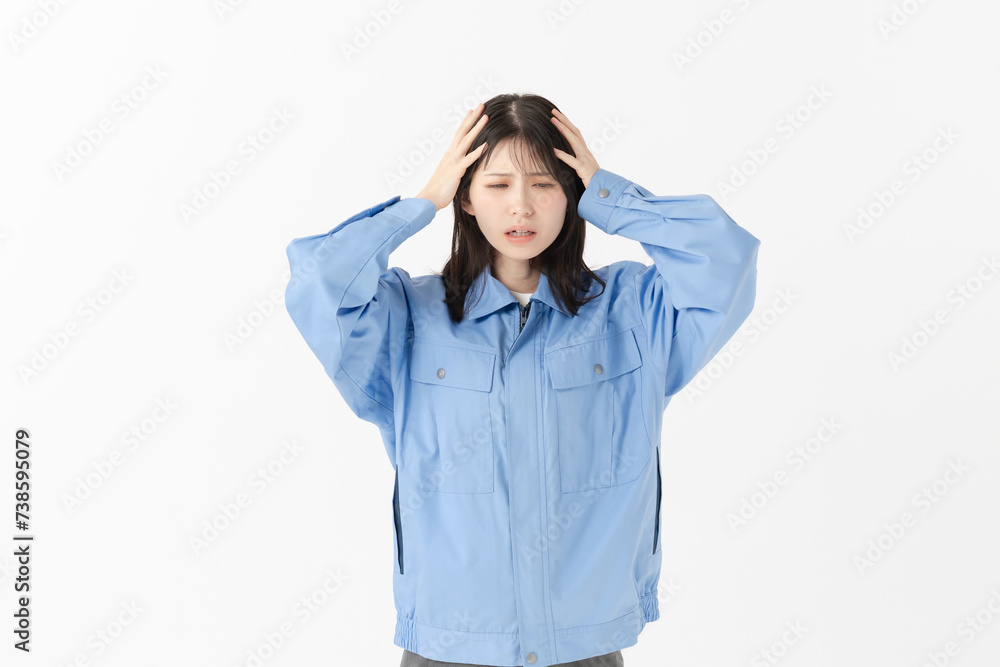 作業服姿で頭を抱える女性 作業服姿で頭を抱える女性
