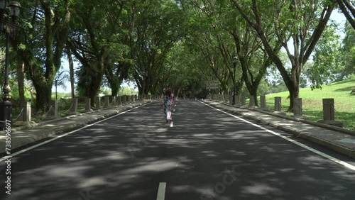 Wallpaper Mural Asian woman in a colored stylish dress with turban walks and dance along the asphalt road under shady trees in the park. Portrait of a woman in motion between trees Torontodigital.ca
