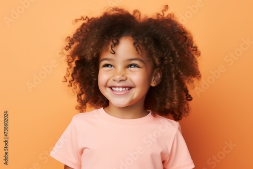 Cheerful african american little girl with curly hair on orange background © Loli