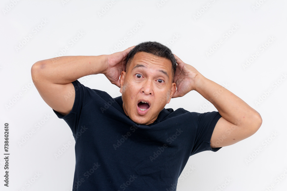 A speechless middle-aged Asian man looking astonished, hands on the back of his head, isolated on a white backdrop. A speechless middle-aged Asian man looking astonished, hands on the back of his head, isolated on a white backdrop.