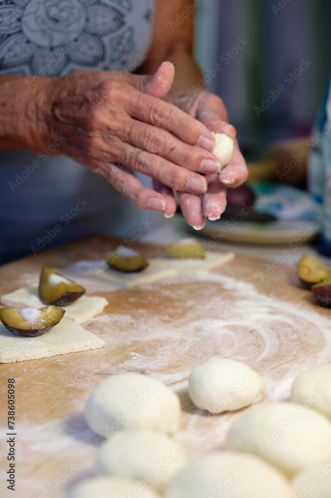 Preparation of homemade fruit dumplings with plums. Czech specialty of sweet good food. Dough on kitchen wooden table with hands. Preparation of homemade fruit dumplings with plums. Czech specialty of sweet good food. Dough on kitchen wooden table with hands.