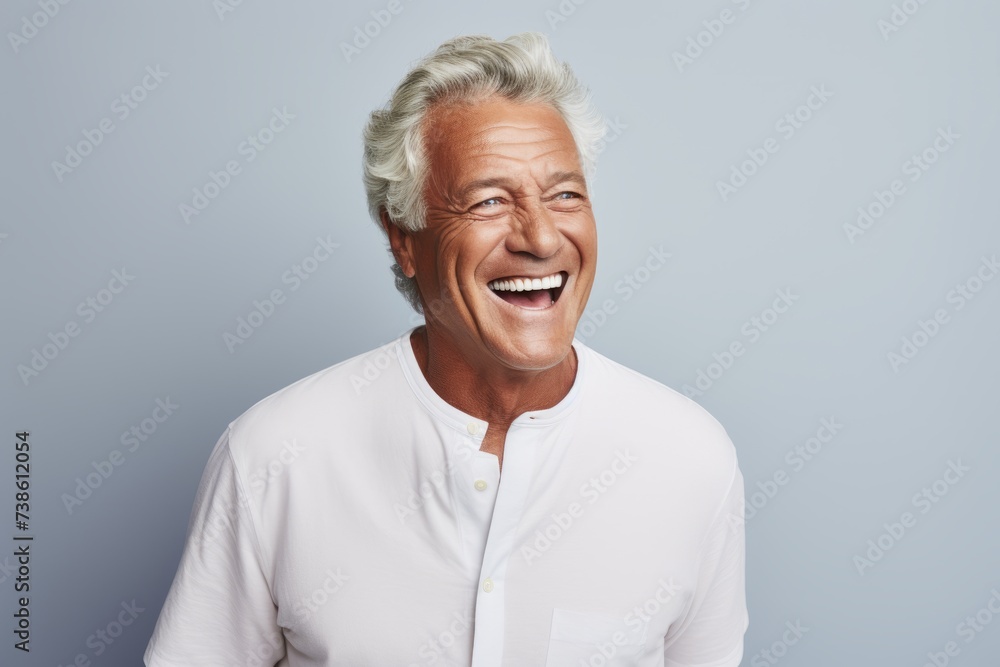 Portrait of a happy senior man laughing and looking at camera against grey background Portrait of a happy senior man laughing and looking at camera against grey background