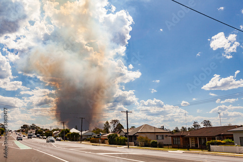 Bushfire smoke billowing into sky behind houses along main street of country town in Hunter Valley photo