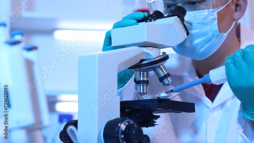 Scientists are doing research in a science lab. A medical chemist in a white coat, gloves and goggles looks at a glass tube. Compare two different liquid samples. and discuss future experiments.