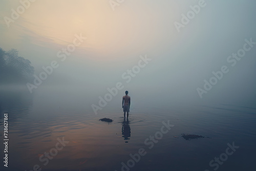 Image of lone man standing in lake in dark dramatic landscape surroundings, mental health concept image