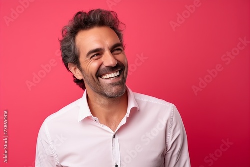 Portrait of a handsome man laughing and looking at the camera over pink background