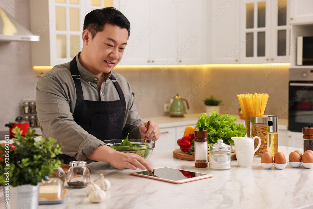 Man using tablet while cooking in kitchen Man using tablet while cooking in kitchen
