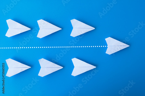 Top view of white paper airplanes origami with one flying ahead against all airplanes