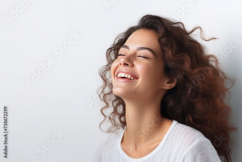 Beautiful young woman with long curly hair laughing and looking up on white background